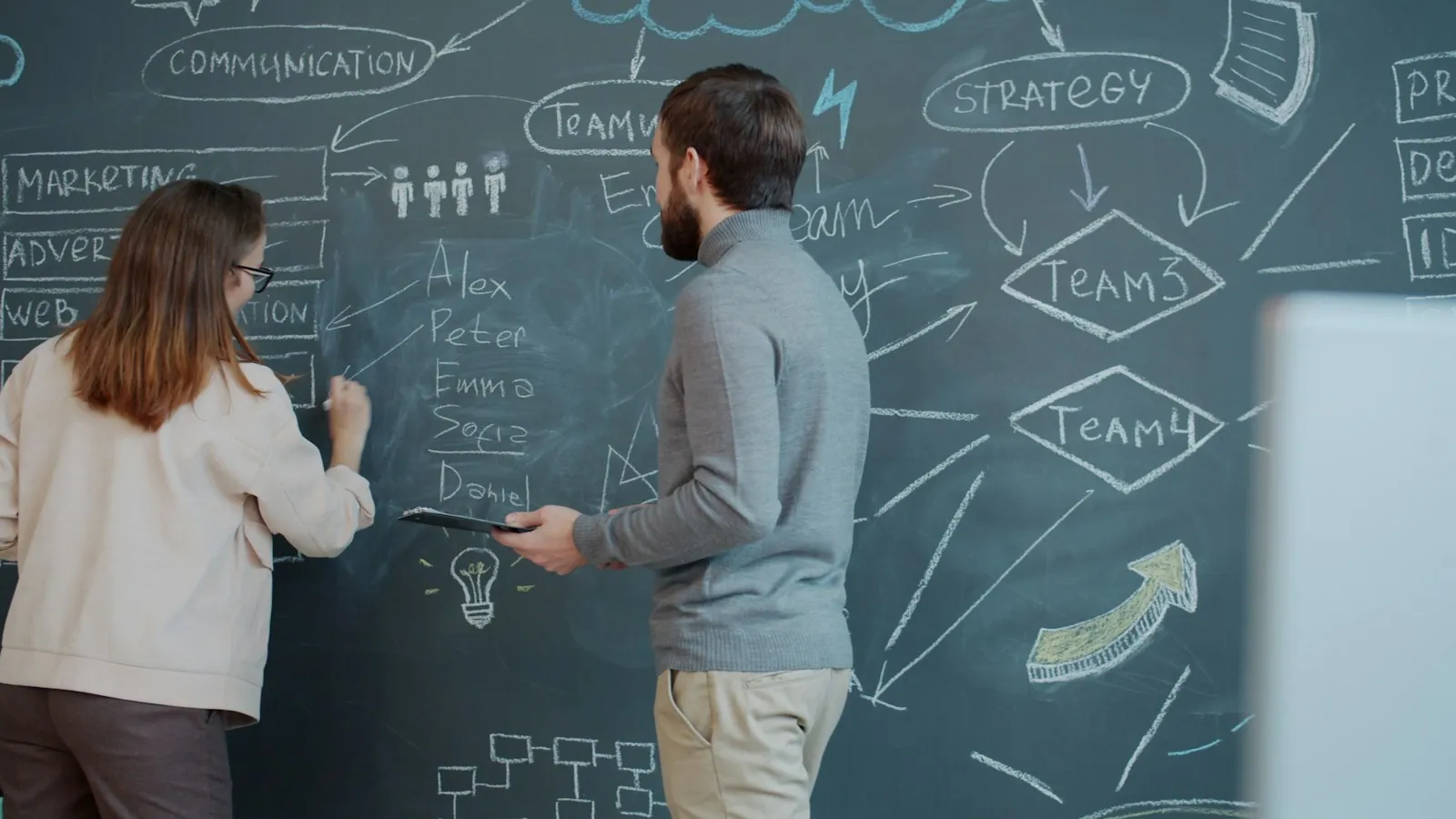 Two colleagues mapping ideas on a chalkboard