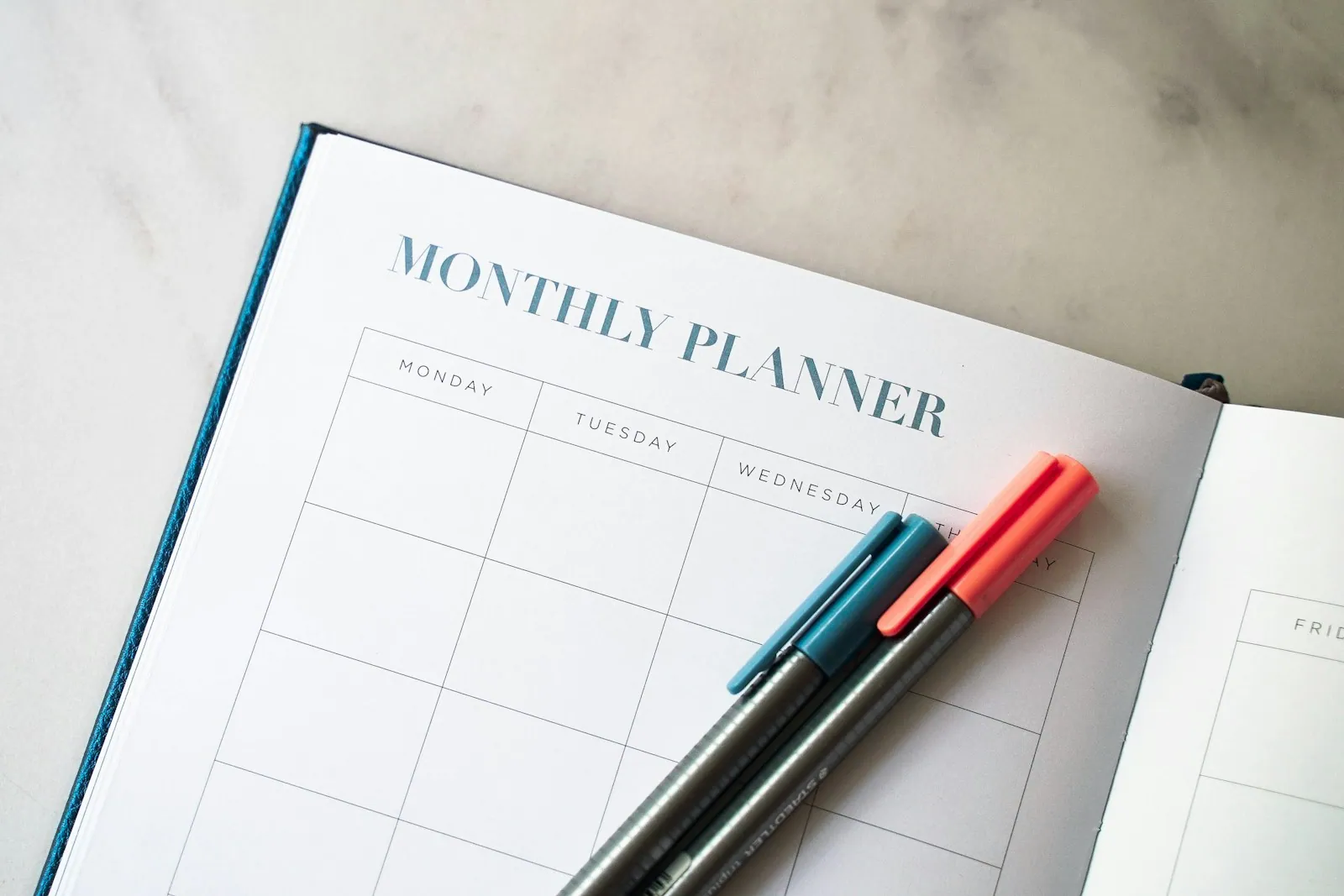A planner and pens arranged on a work surface