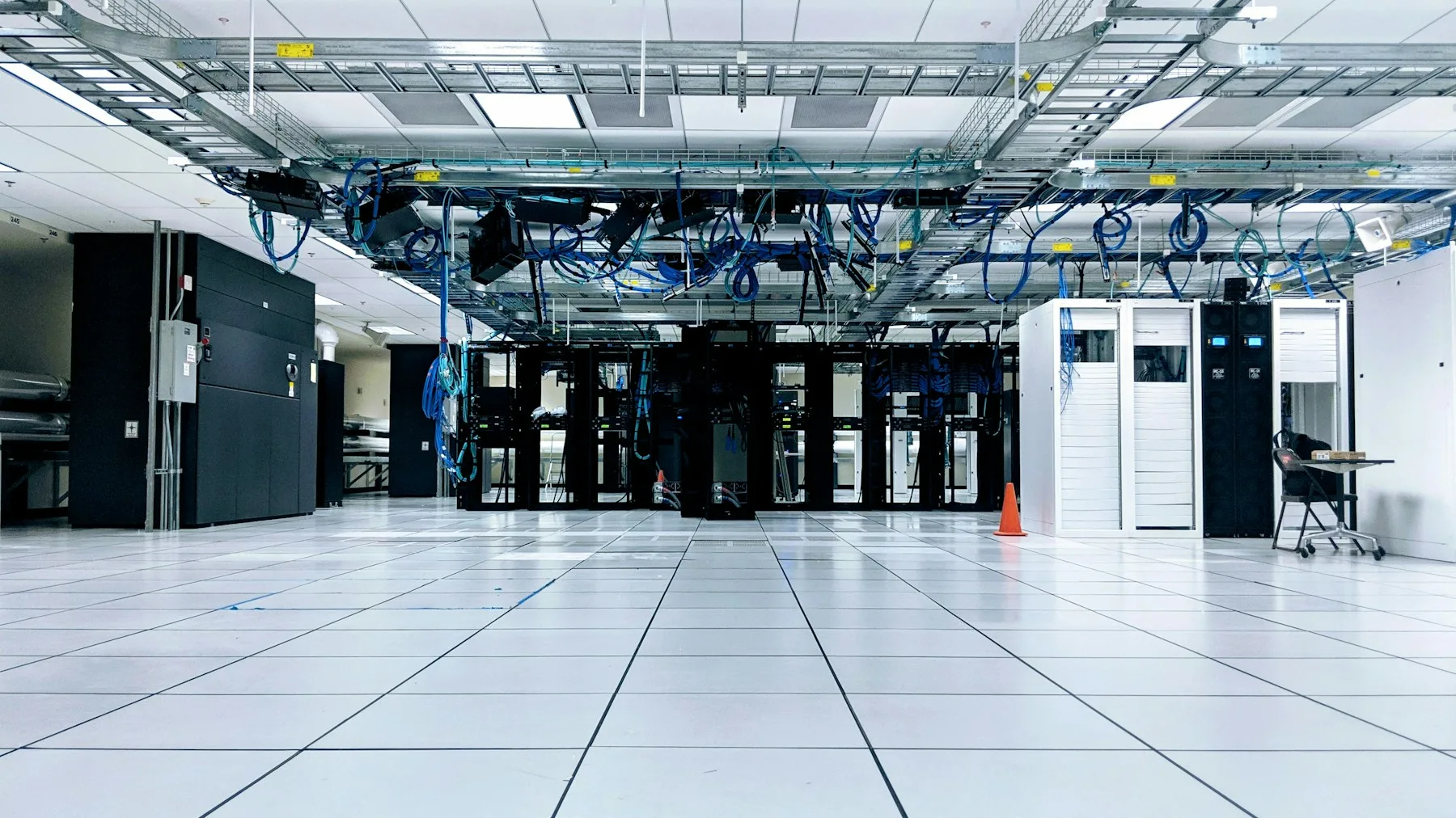 A wide view of data-centre cabinets beneath network cabling