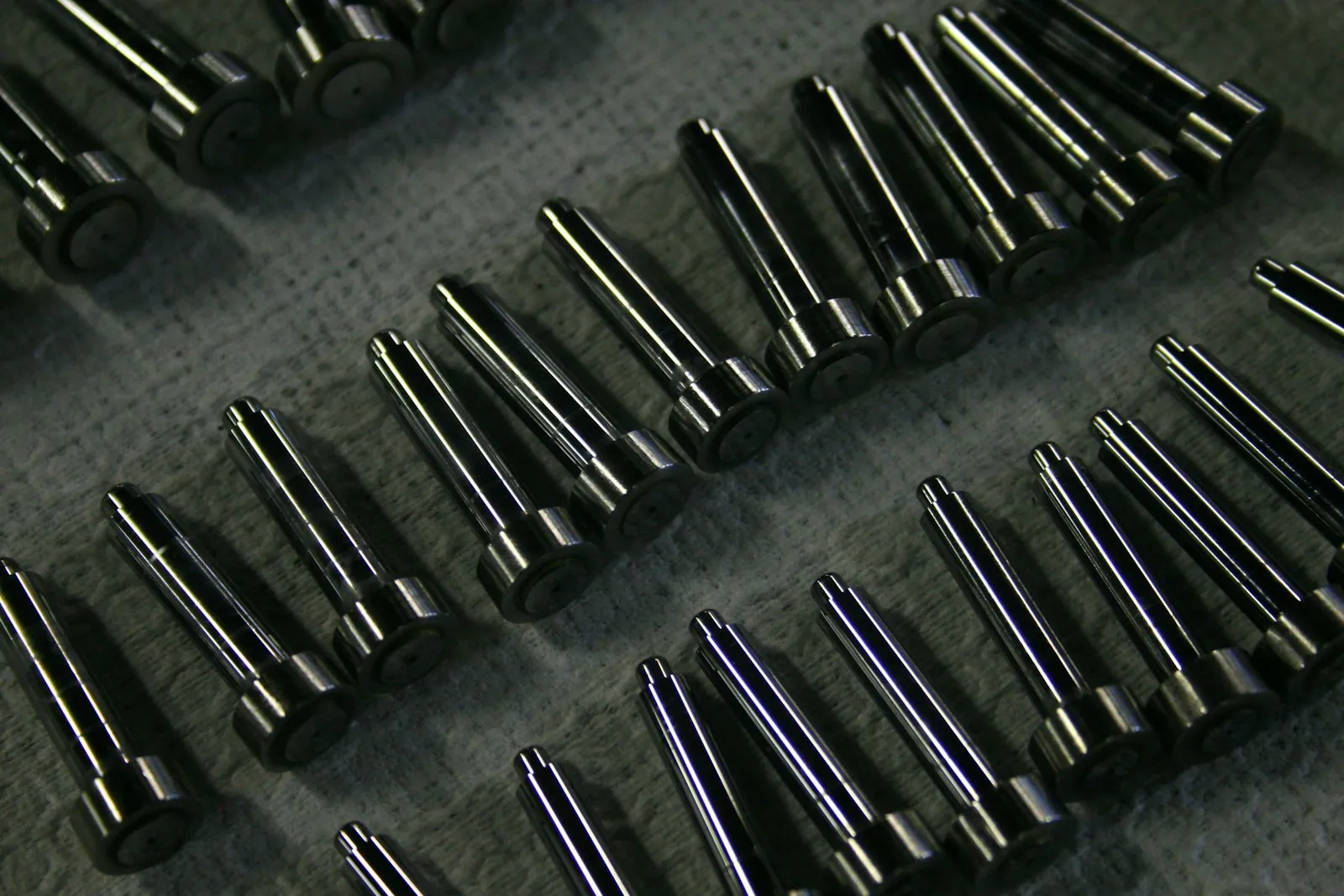 Rows of machined metal components on a textured work surface